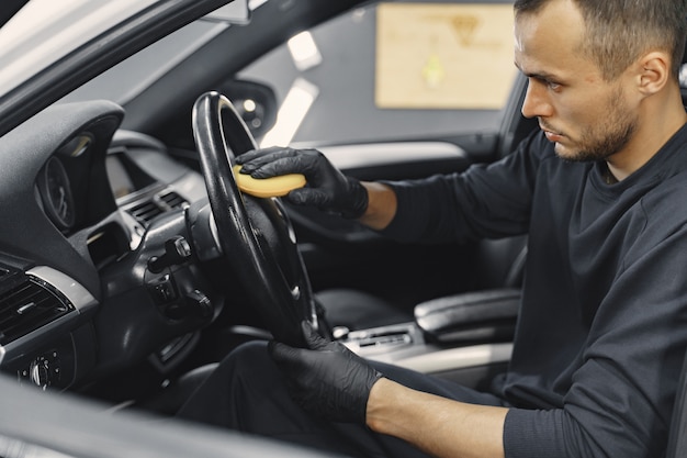 Man polish salon of car in a garage