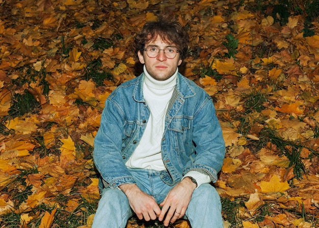 Free photo man posing next to autumn leaves