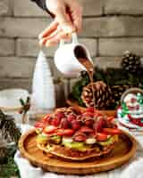 Free photo man pouring chocolate on waffle with fruit slices