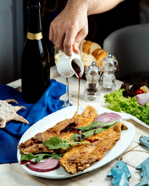 Free photo man pouring nar sharab pomegranate sauce on fried fish