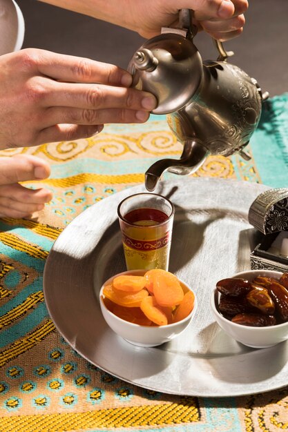 Man pouring tea in tiny cup high view