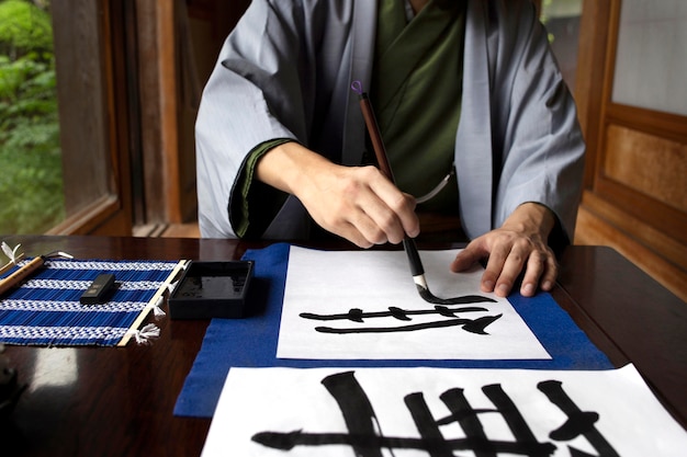 Man practicing japanese handwriting with an assortment of tools