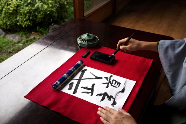 Man practicing japanese handwriting with an assortment of tools