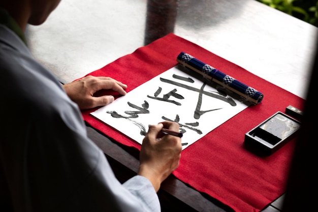 Free photo man practicing japanese handwriting with an assortment of tools