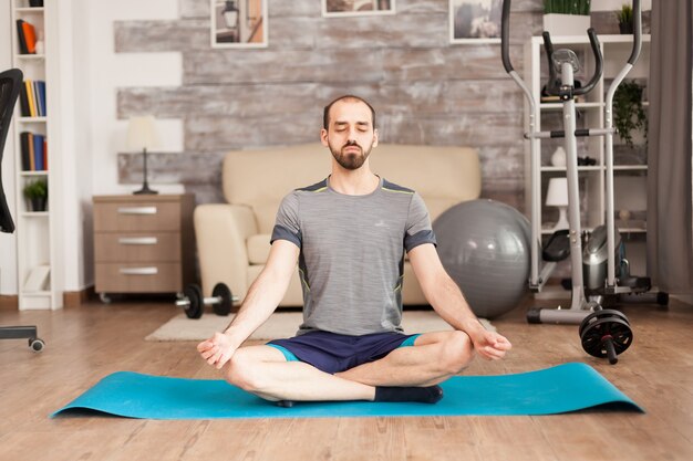 Man practicing mindfulness on yoga mat on mat during global isolation. Swiss ball in the background.