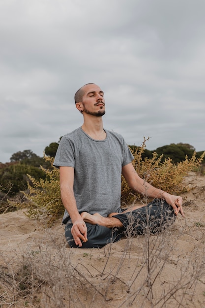 Free Photo man practicing yoga outdoors