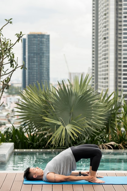 Free photo man practicing yoga position by the pool