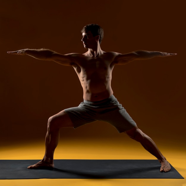 Free photo man practicing yoga positions on mat