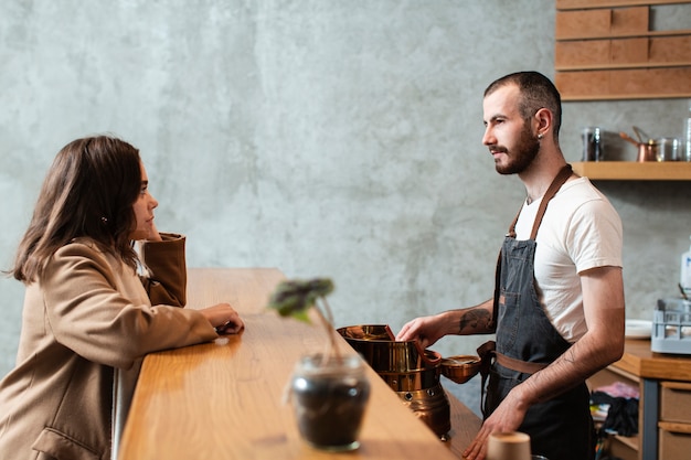 Man preparing coffee and talking to woman