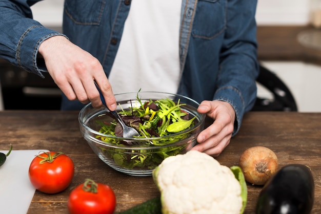 Free Photo man preparing salad in kitchen