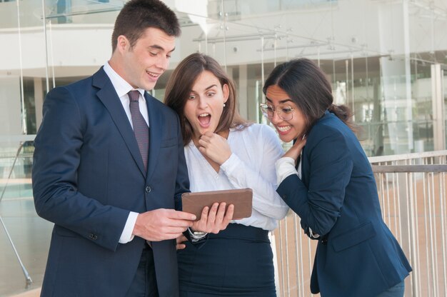 Man presenting colleagues data on tablet, they looking shocked