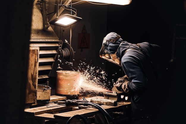 Free photo man in protective mask is cutting metal and sparks are flying away.