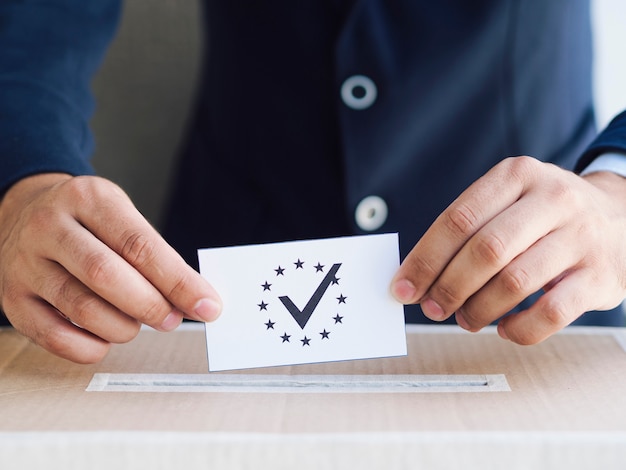 Free photo man putting a ballot in a box