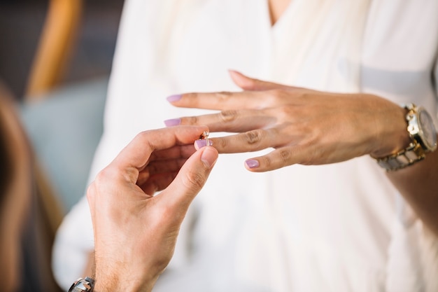 Man putting engagement ring on his fiancee's finger