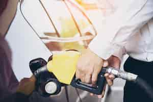 Free photo man putting gasoline fuel into his car in a pump gas station