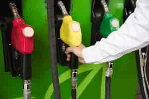 Free photo man putting gasoline fuel into his car in a pump gas station