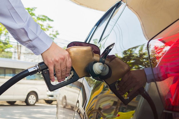 Free photo man putting gasoline fuel into his car in a pump gas station