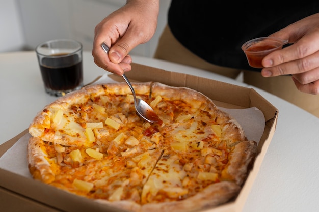 Free photo man putting sauce on pizza