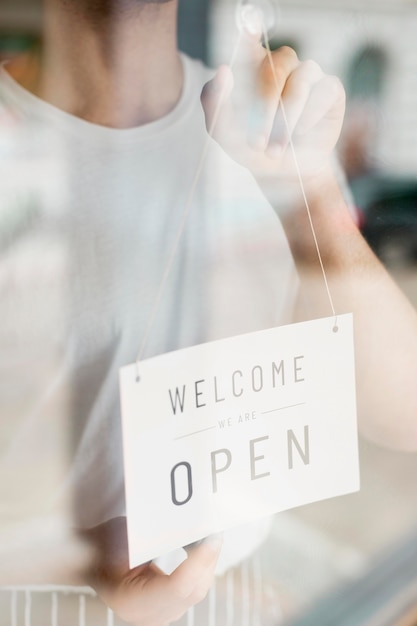 Free Photo man putting up open sign on coffee shop window