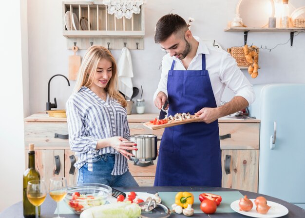 Man putting vegetables from board in pot