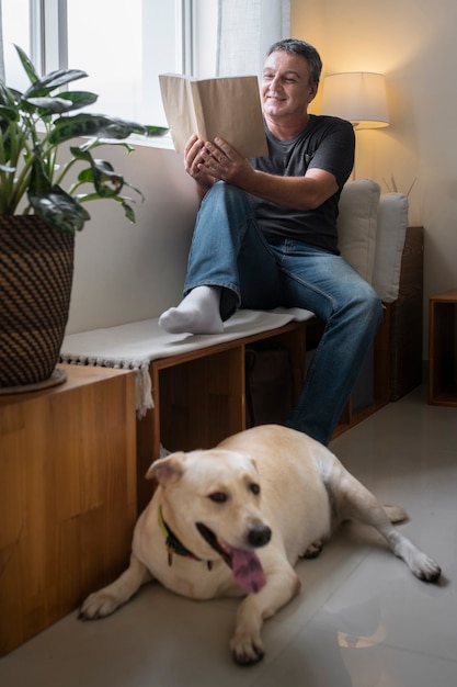 Free photo man reading at home with his dog companion