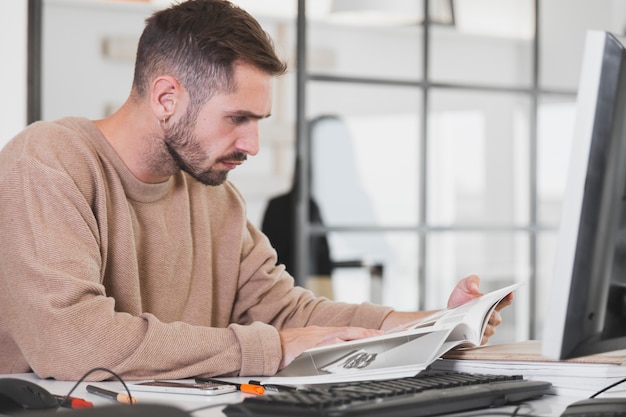 Free photo man reading magazine in office