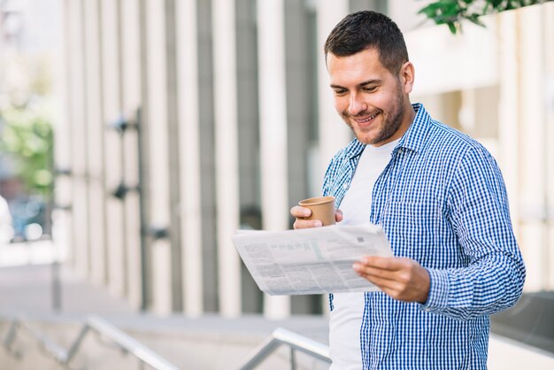 Man reading newspaper near building