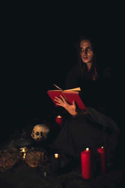 Man reading a red spell book in the dark