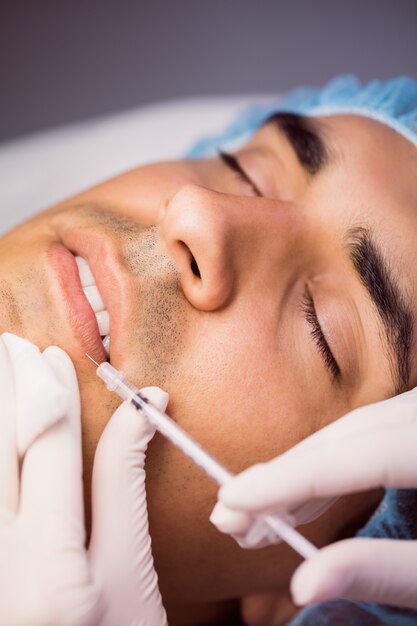 Man receiving botox injection on his lips