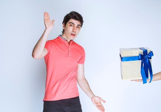 Man receiving and holding a white gift box wrapped with blue ribbon with both hands