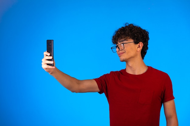 Man in red shirt taking selfie or making a phone call and having fun.