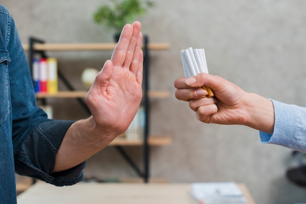 Man refusing bunch of cigarettes offered by his female friend