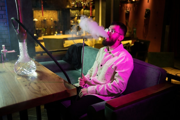 Free Photo man relaxing by vaping from a hookah in a bar