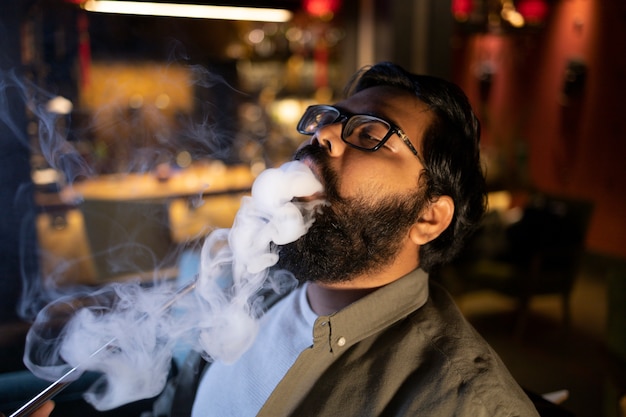 Man relaxing by vaping from a hookah in a bar