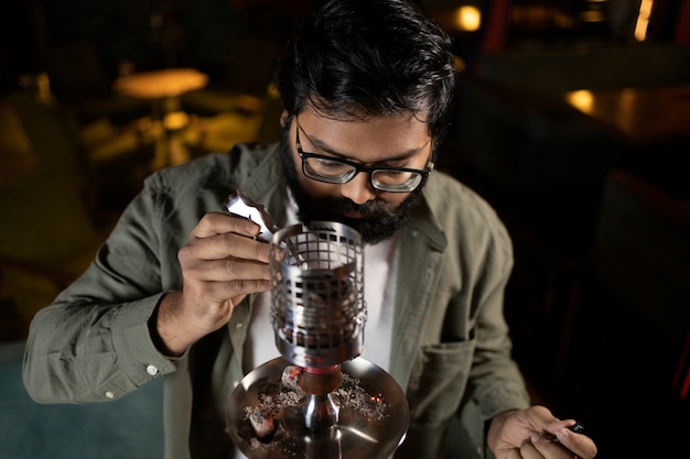 Free photo man relaxing by vaping from a hookah in a bar