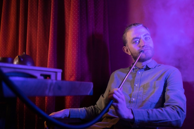 Man relaxing by vaping from a hookah in a bar