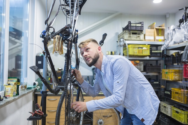 Free photo man repairing bicycle in workshop