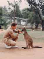 Free photo man in the reserve is playing with a kangaroo