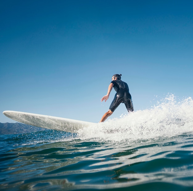 Free photo man riding his surfboard side view