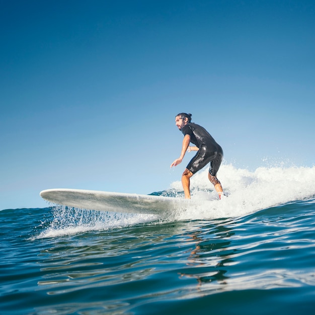 Free photo man riding his surfboard