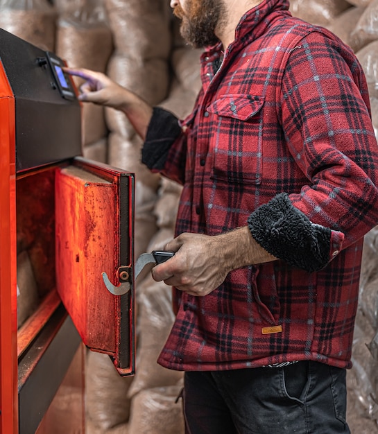 A man in a room with a solid fuel boiler, working on biofuel, economical heating.