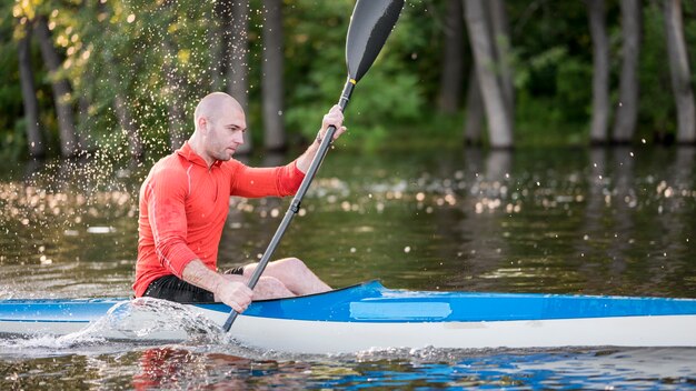 Man rowing in blue canoe side view