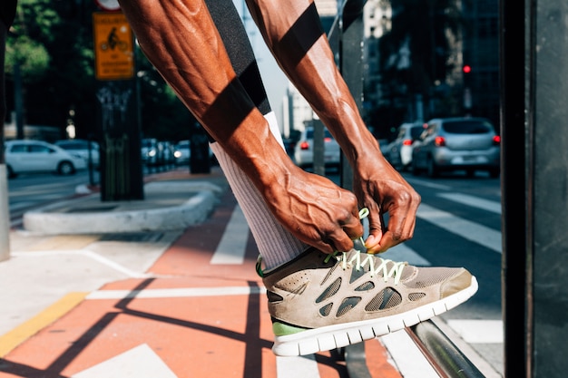 Free photo man runner tying lace of shoes for sport training on road