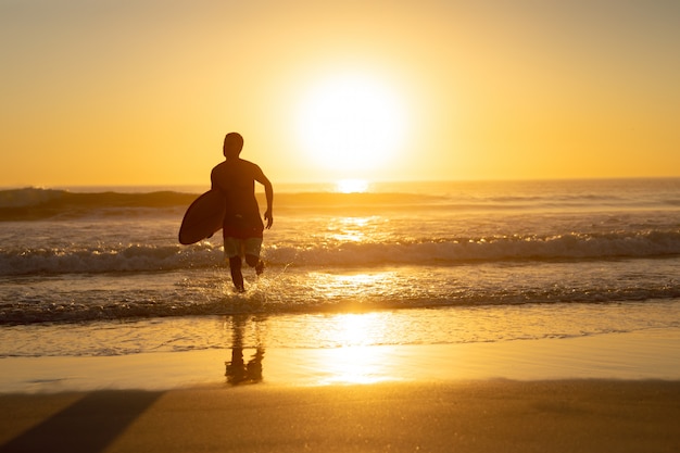 Man running with surfboard on the beach