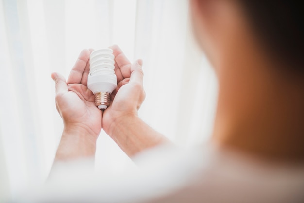 Man's hand holding compact fluorescent light bulb