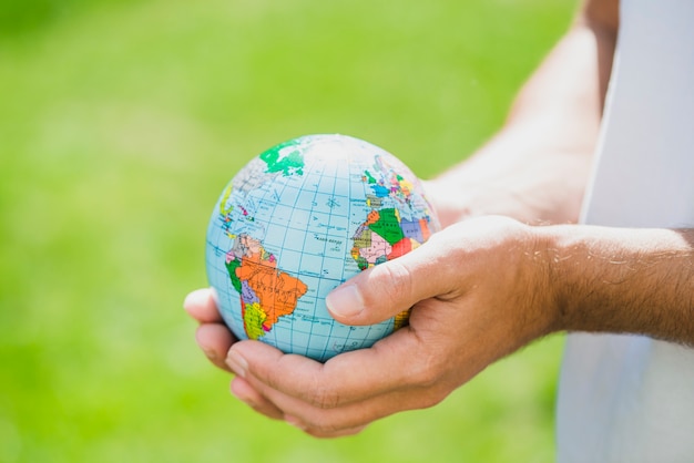 Free photo man's hand holding small globe