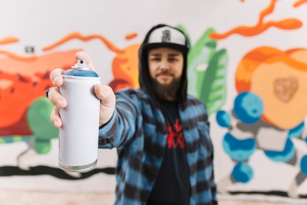 Man's hand holding white aerosol can