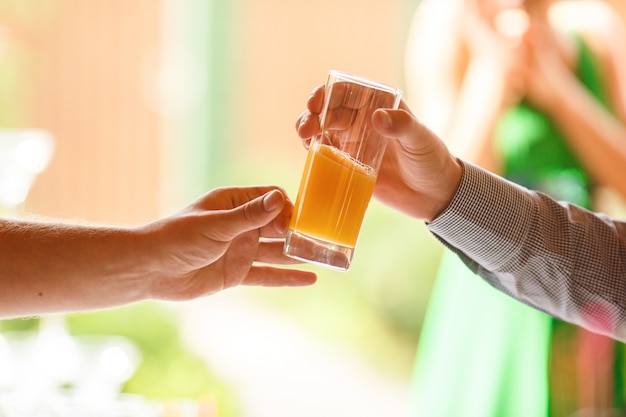 Man's hand reach out a glass with fresh juice to another man