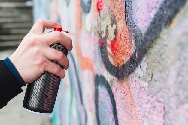 Free photo man's hand spraying red paint with spray bottle