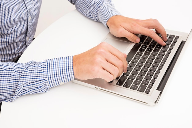 Man's hand typing on laptop over the white table